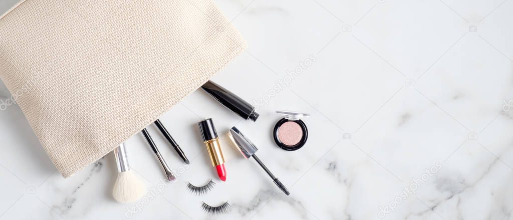 Cosmetic bag with makeup products on marble desk. Top view with copy space. Beauty salon banner design template