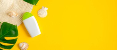 Güneş kremi şişesi ve sarı arka planda tropikal yapraklar. Düz yerde, üst tarafta. Güneş koruması, güneş kremi kozmetik ürünü, yaz cilt bakımı konsepti