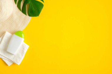 Güneş kremi kozmetik ürünleri ve sarı arka planda yaz tatili plaj aksesuarları. Düz konum, üst görünüm, kopyalama alanı. Güneş koruması ve cilt bakımı kavramı