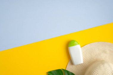Sarı ve mavi arka planda tropikal yaprak ve kadın şapkası olan güneş kremi şişesi modeli. Güneş koruması ve plaj cilt bakımı kavramı