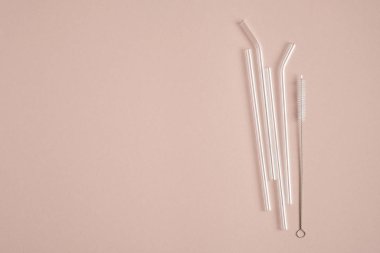Kahverengi arka planda temizleme fırçası olan tekrar kullanılabilir cam pipetler. Düz yerde, üst tarafta. Sıfır atık, plastiksiz konsept. Sürdürülebilir yaşam tarzı.