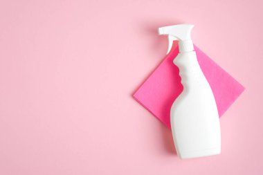 Boş temizlik spreyi şişesi ve pembe arka planda bir bez parçası. Düz yerde, üst tarafta. Ev temizliği ve temizlik konsepti.