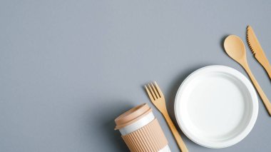 Çevre dostu bambu takımı, kağıt tabak ve gri arka planda yeniden kullanılabilir kahve kupası. Sıfır atık, plastik sofra takımı. Sürdürülebilir yaşam tarzı konsepti. Eko mağazası afiş tasarımı