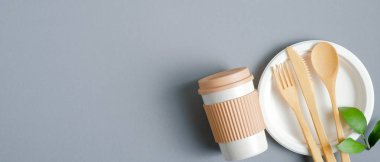 Çevre dostu bambu çatal bıçak takımı ve gri arka planda yeniden kullanılabilir kahve fincanı. Sıfır atık çatal bıçak konsepti. Üst görünüm, boşluğu kopyala. Eko mağazası afiş tasarımı