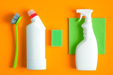 Turuncu arka planda temizlik aletleri var. Ev temizliği ve oda servisi konsepti. Düz yatış, üst görünüm.