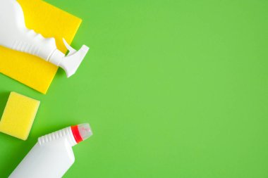 Yeşil arka planda temizlik aletleri ve malzemeler. Ev temizliği ve oda servisi konsepti. Düz yatış, üst görünüm.