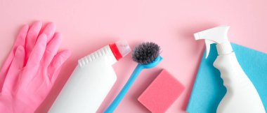 Pembe arka planda temizlik aletleri ve malzemeler. Ev temizliği ve oda servisi konsepti. Düz yatış, üst görünüm.