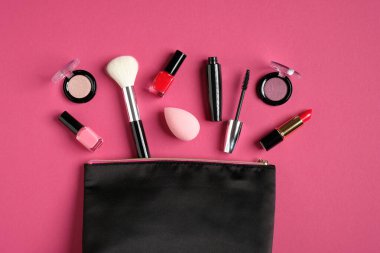Kozmetik çanta ve makyaj ürünleri pembe arka planda. Düz yerde, üst tarafta. Güzellik ve moda konsepti.