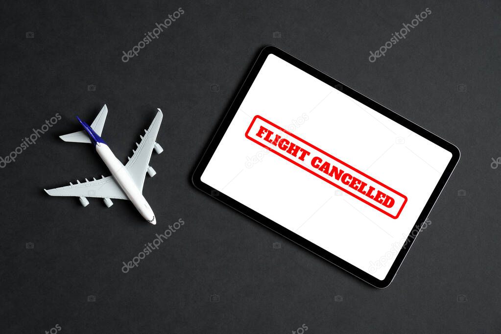 Flight cancelled concept. Plane model and tablet with sign 
