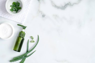 Aloe vera spa tedavi konsepti. Aloe vera jeli yeşil şişe, el kremi ve mermer zemin üzerinde dilimlenmiş aloe vera kökü. Organik doğal cilt bakım ürünleri