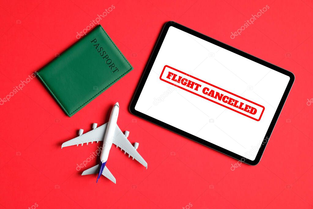 Flight cancellation due to the impact of coronavirus (COVID-19) concept. Plane toy, passport, and tablet with text 