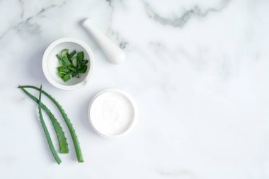 Kozmetik krem kavanozu ve mermer zemin üzerinde yeşil dilimlenmiş aloe vera kökü. Organik nemlendirici yüz kremi. Yüz bakımı ve güzellik tedavi konsepti