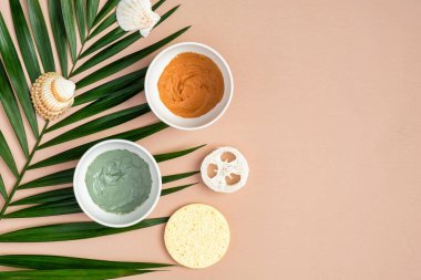 Şeftali rengi arka planda, tropikal palmiye yapraklı çamur maskeler. SPA doğal organik kozmetik ürünleri, yaz yüz bakımı konsepti. Üst manzara, düz uzanma.