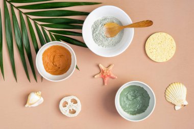 Şeftali arka planında tropikal palmiye yaprağı ve deniz kabuğu olan doğal organik kil maskeler. Yaz yüz bakımı konsepti. Üst manzara, düz uzanma.