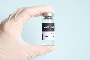 Coronavirus COVID 19 aşı tüpünü tutan tıbbi eldiveni teslim edin.