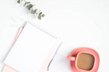 Kağıt defter ve pembe kahve fincanı olan şık bir kadın çalışma alanı. Modern minimal stil kadınsı ofis masası konsepti