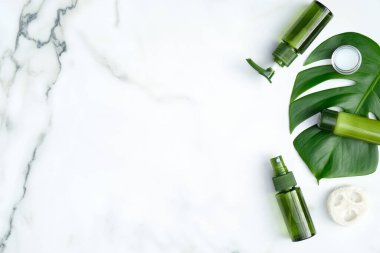 Mermer zemin üzerinde tropikal yaprağı olan organik güzellik ürünleri. SPA kozmetik, güzellik tedavi konsepti. Düz konum, üst görünüm, kopyalama alanı