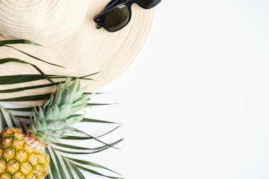 Yaz tatili konsepti. Üst manzara kadın hasır plaj şapkası, güneş gözlüğü, ananas, arka planda palmiye yaprağı.