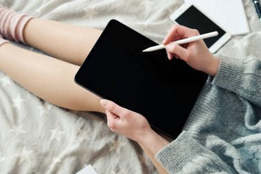 Evde dijital tablet çizerek çalışan serbest çalışan genç bir bayan tasarımcı, yakın çekim görüntüsü. Evde çalışmak, güvende kalmak, uzak eğitim kavramı. Hygge, rahat stil