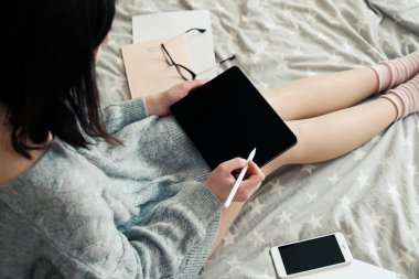 Evde dijital tablet çizerek çalışan serbest çalışan genç bir bayan tasarımcı, yakın çekim görüntüsü. Evde çalışmak, güvende kalmak, uzak eğitim kavramı. Hygge, rahat stil.