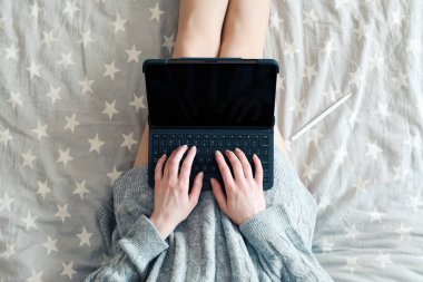 Üst düzey bir kadın evdeki yatağında dizüstü bilgisayar kullanıyor. Samimi, kızlık zarı tarzı. Çevrimiçi alışveriş, çalışma evi, serbest çalışma, çevrimiçi öğrenme, öğrenim konsepti. Uzaklık eğitimi
