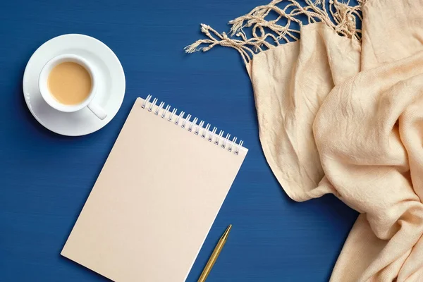 在经典的蓝色背景上平铺着一杯咖啡 纸笔记本和毛毯 俯瞰舒适的家书桌 笨重的 快乐的早晨概念 — 图库照片