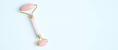 Mavi arka planda Rose Quartz yüz silindiri. Yüz bakımı için masaj aleti, SPA güzellik tedavisi konsepti. Düz yatış, üst görünüm