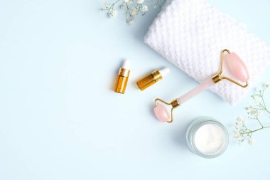 Nemlendirici kremi ve mavi arka planda gerekli yağı olan yeşim yüzlü silindir. Düz yerde, üst tarafta. Yüz bakımı için masaj aracı, SPA güzellik tedavi konsepti