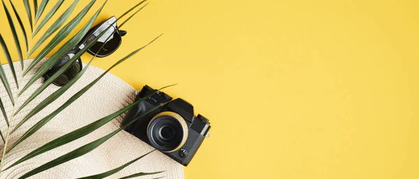 Summer banner template with straw hat, fashion sunglasses, vintage camera. Top view summer background with traveler accessories and tropical palm leaf. Summer holiday vacation, travel, tourism concept