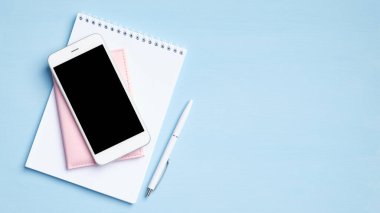 Kağıt defter, belge, kalem, telefon ve mavi arka planı boş olan modern ofis masası. İş konsepti. Üst manzara, düz uzanma