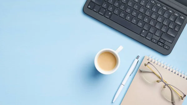 博客工作空间与笔记本电脑键盘 粉红色的纸笔记本 一杯咖啡 蓝色背景的钢笔 简约风格的家庭写字台 顶视图 商业和技术概念 — 图库照片