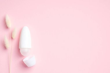 Pembe arka planda kuru çiçekli boş deodorant şişesi. Doğal organik terleme önleyici, terleme konsepti. Düz yatış, üst görünüm