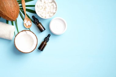 SPA doğal hindistan cevizi nemlendirici krem ve mavi arka planda palmiye yaprağı ile gerekli yağ. Düz yerde, üst tarafta. Vücut tedavisi için organik güzellik ürünleri, cilt bakımı konsepti