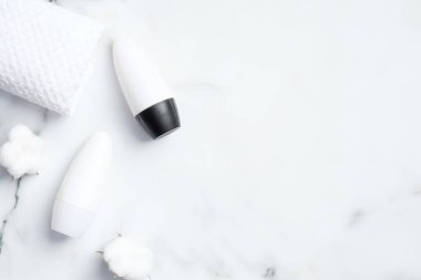 Pamuk çiçekli deodorant şişeleri ve mermer arka planda havlu. Düz yerde, üst tarafta. Koltuk altı cilt bakımı, ter koruması konsepti