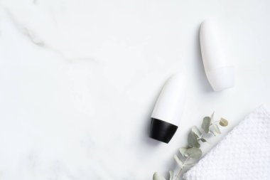 Deodorant şişeleri okaliptüs ve mermer zemin üzerinde havlu. Düz yerde, üst tarafta. Boş terleme önleyici ambalaj, terleme önleyici ürün konsepti