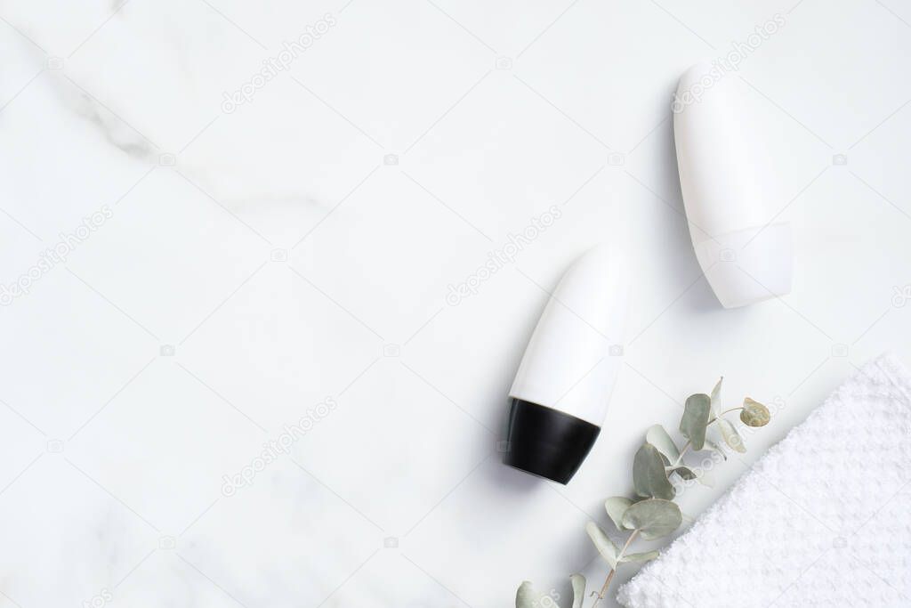 Deodorant bottles mockups with eucalyptus and towel on marble background. Flat lay, top view. Blank antiperspirant packaging, sweat protection product concept