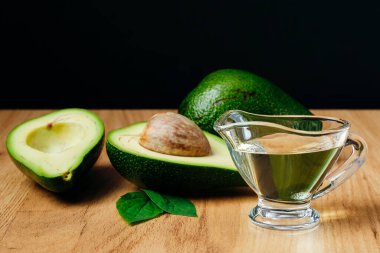 Avokado yağı ve olgun taze avokado ahşap masanın üzerinde, yakın plan.