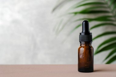 Düşürme şişesi modeli. Bir şişe koyu kehribar cam ve gerekli yağ ve tropikal yaprak. Doğal organik kozmetik, aromaterapi mesaj yağı.