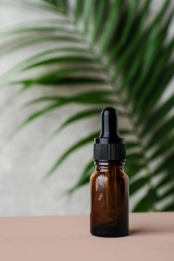 Kehribar cam damlası şişesi, gerekli yağ ve tropikal yaprak. Doğal bitkisel kozmetik ürünü, aromaterapi mesajı yağı..