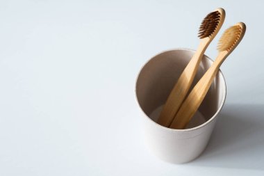Beyaz arka planda cam içinde çevre dostu doğal bambu diş fırçaları. Biyolojik çözünebilir plastik banyo aksesuarı. Sıfır atık, sürdürülebilir yaşam tarzı kavramı