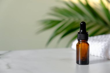 Tuvaletteki mermer masanın üzerinde havlu olan gerekli yağ şişesi. Palmiye yaprağıyla serum temizleyici şişesi. SPA doğal organik kozmetik, cilt için aroma yağı.