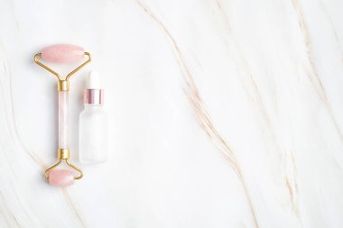 Serumlu yüz masajı silindiri ya da mermer arka planda gerekli yağ şişesi. Düz konum, üst görünüm, kopyalama alanı. Yüz bakımı, vücut tedavisi konsepti.