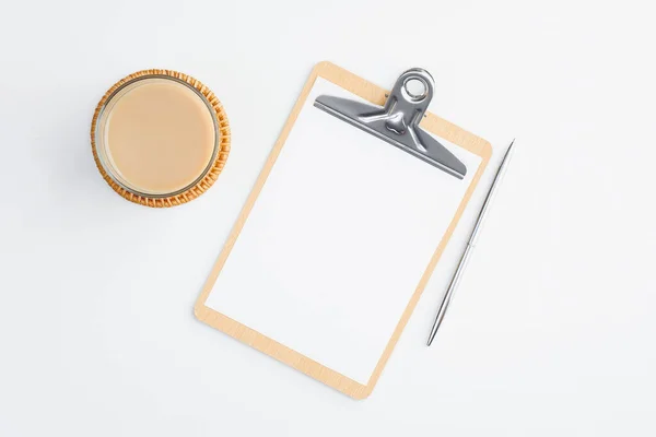 Clipboard with empty note and cup of coffee on white table. Flat lay, top view. Modern office desk concept.