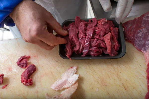 Butcher cutting beef in butcher shop for selling