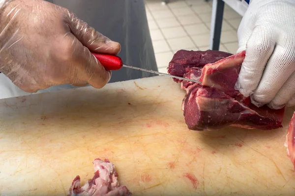 Butcher carving meat for salling in meat workshop