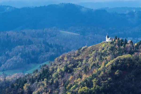 Autumn panorama with christian church on top of hill in Slovenian countryside