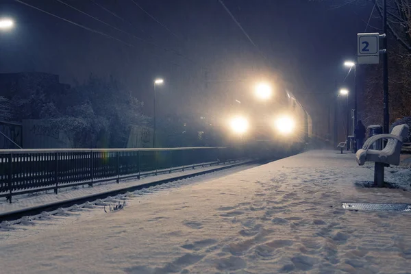 Train with strong headlights arriving at station on a snowy night — Stock Photo, Image