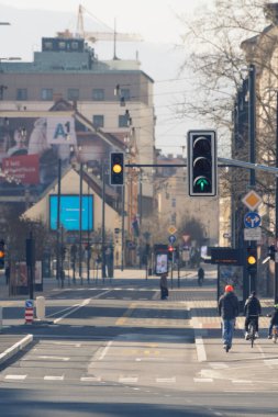 Ljubljana, Slovenya - 17 Mart 2020: Coronavirus Covid-19 salgını sırasında az sayıda bisikletli ve yaya ile Slovenya 'nın Ljubljana kentindeki trafik ışıklarında çalışmak
