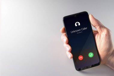 Erkek, ekranda bilinmeyen bir arayanın bulunduğu akıllı telefonu tutuyor. Mahremiyet, dolandırıcılık, siber suç ve casusluk kavramları