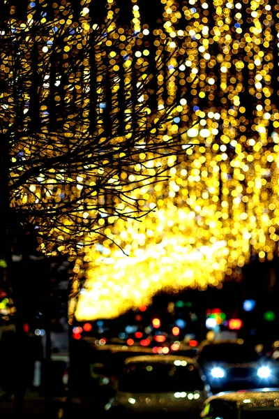 Jasne kręgi z latarni ulicznych i reflektorów samochodów na nieostrym zdjęciu z ulicy nocnej. — Zdjęcie stockowe